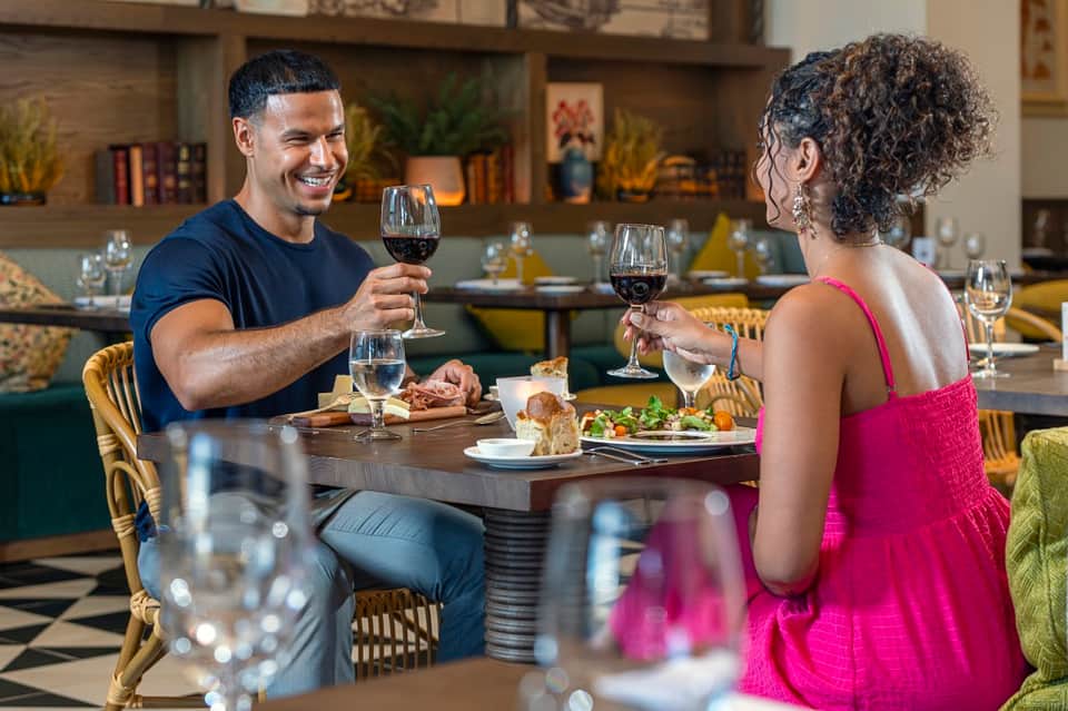 Couple dining together indoors with wine glasses, plated food, and modern restaurant interior