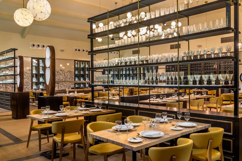 Upscale restaurant interior with yellow chairs, black shelving, and wine display