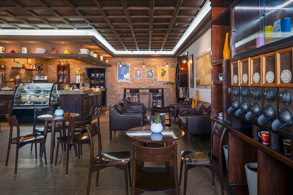Upscale hotel lounge with exposed brick, dark leather seating, bar counter, and decorative displays