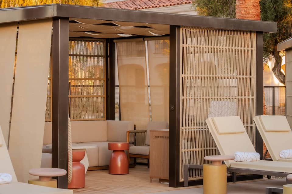 Modern outdoor cabana with lounge seating, woven screens, and adjacent loungers on deck