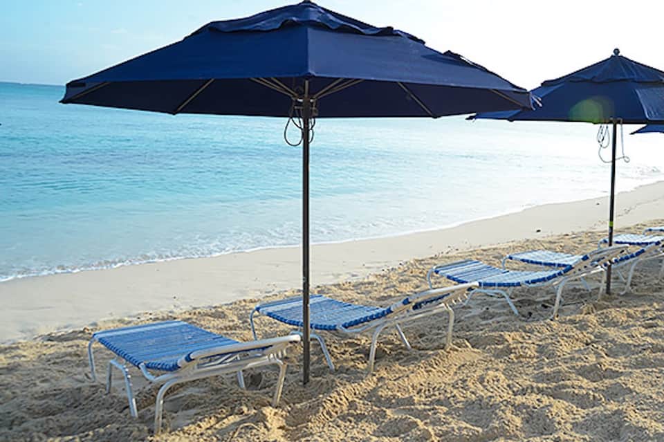 Blue umbrellas and lounge chairs on sandy beach with clear turquoise ocean water