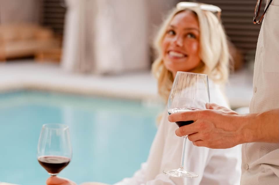 Woman enjoying wine poolside at resort with blurred pool backdrop