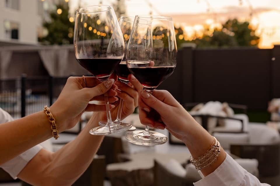 Three glasses of red wine toasting at sunset on an outdoor rooftop terrace