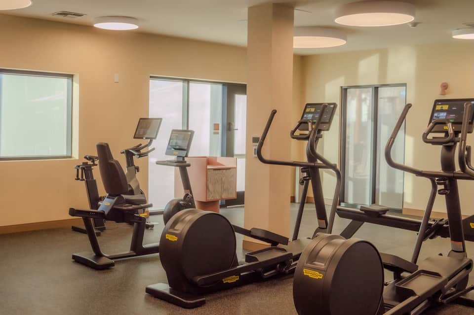 Hotel fitness center with cardio equipment, exercise bikes, and glass-walled fitness rooms
