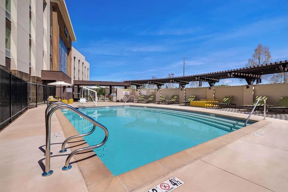 Resort swimming pool with turquoise water, loungers, and modern building architecture