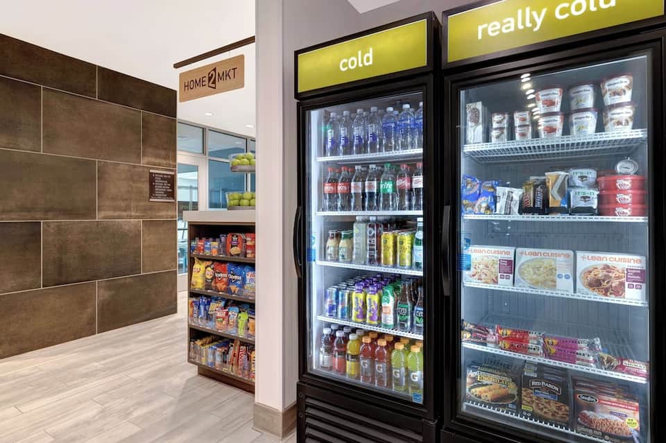 Hotel convenience market interior with refrigerated beverage cases and snack shelving