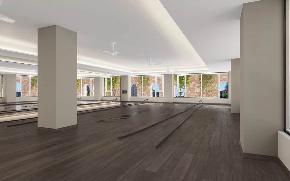 Spacious fitness center with mirrored walls, wooden flooring, and bright windows