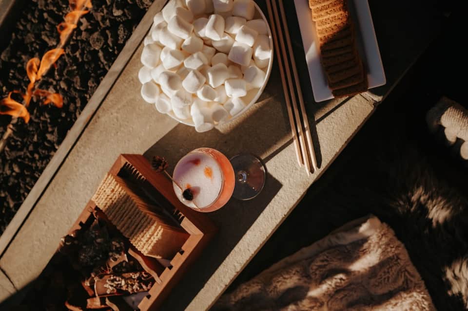 Overhead view of spa amenities including marshmallows, cocktail, and relaxation items on textured surface