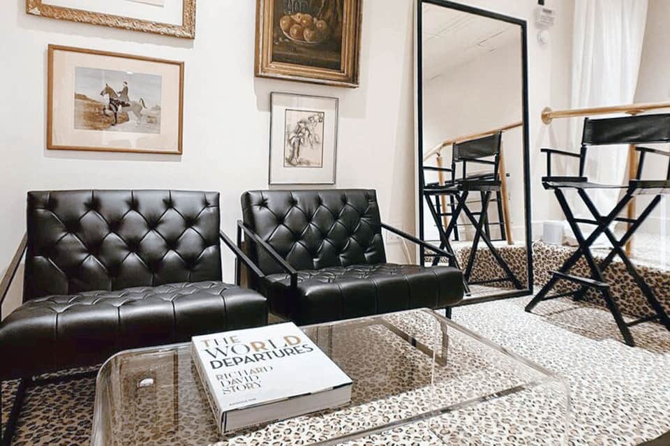 Classic spa relaxation room with black leather seating, framed artwork, and large mirror