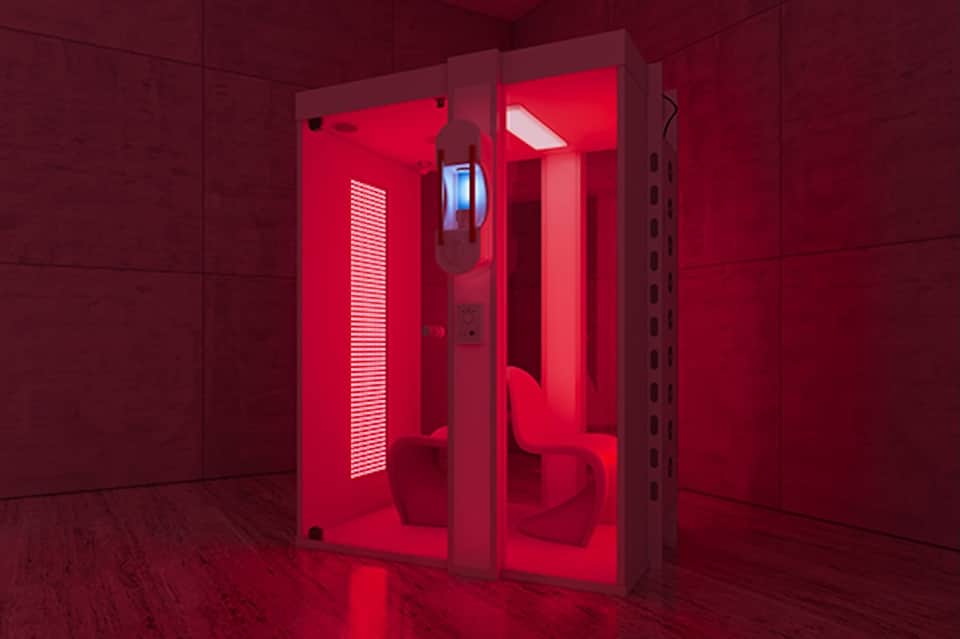 Red-lit infrared sauna pods in spa facility with glass doors