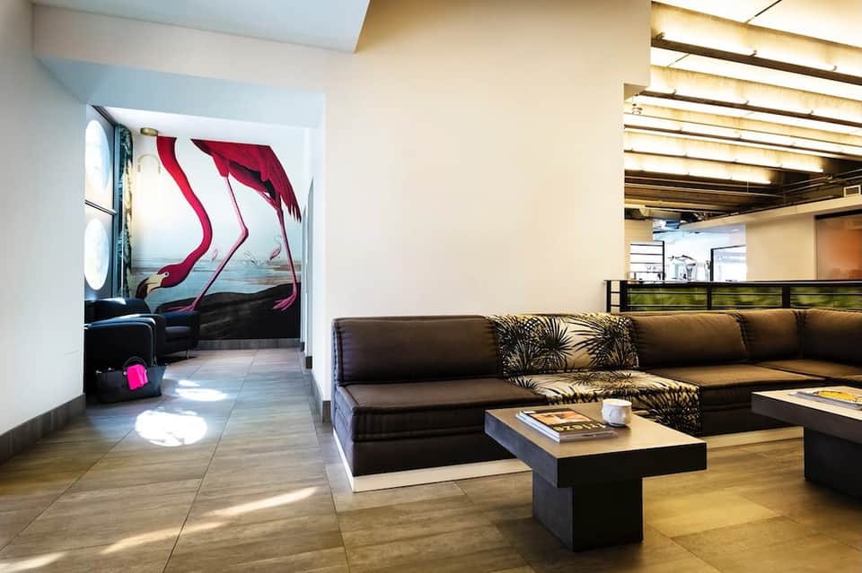 Modern lounge with black sectional sofa, abstract wall art, and wooden ceiling details