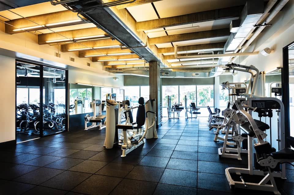 Modern fitness center with exercise equipment, large windows, and contemporary lighting design