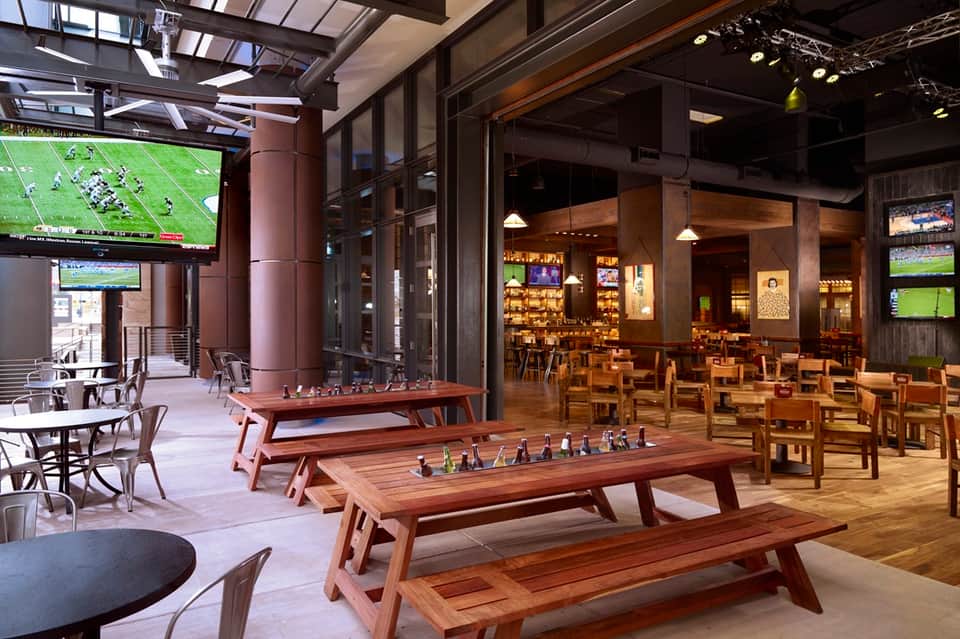 Recreation room with foosball tables, bar seating, sports screens, and modern lighting