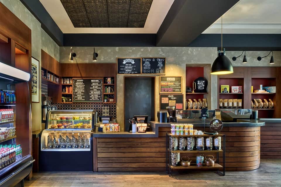 Modern café interior with dark wood shelving, menu boards, and retail displays