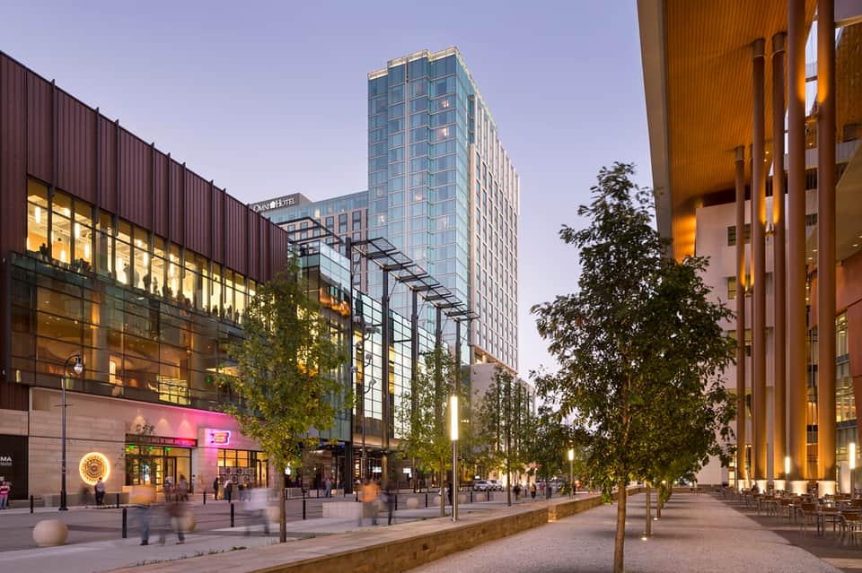 Urban downtown plaza at dusk with modern buildings, shops, and pedestrian walkway