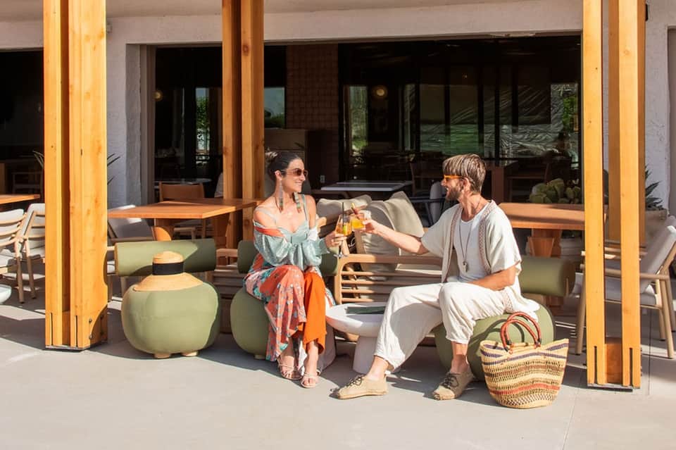 Couple enjoying drinks on patio with modern seating and large windows overlooking grounds
