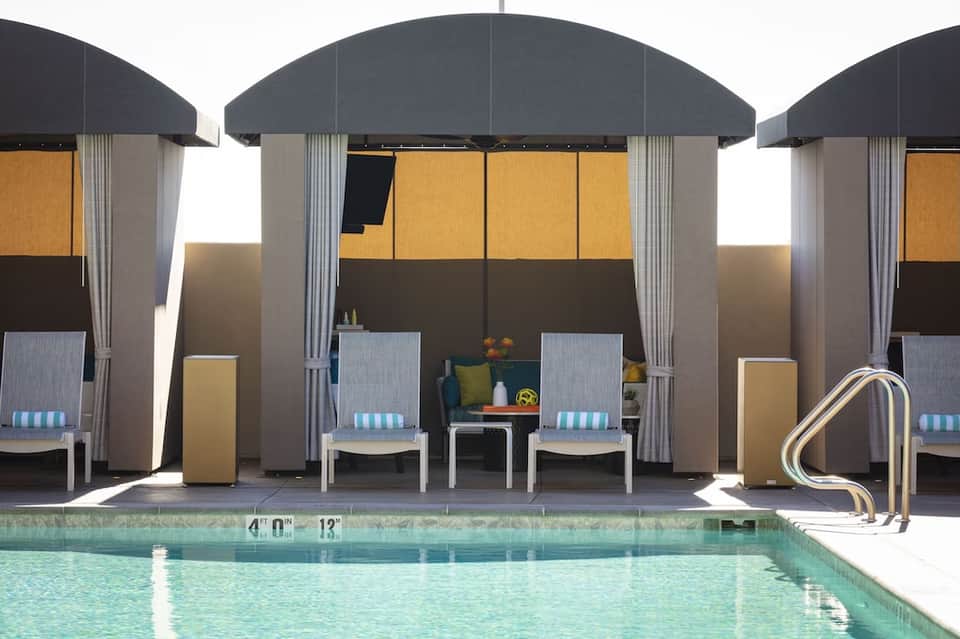 Three dark dome-shaped cabanas with white loungers positioned poolside, featuring modern architectural design
