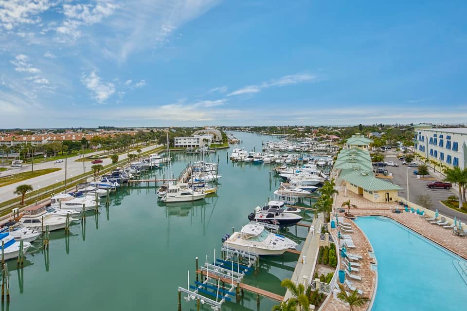 Aerial marina resort view with boats, pools, palm trees, and waterway docks