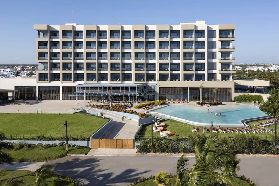 Modern beachfront resort building with pool, spa, manicured lawns, and beach access in daylight