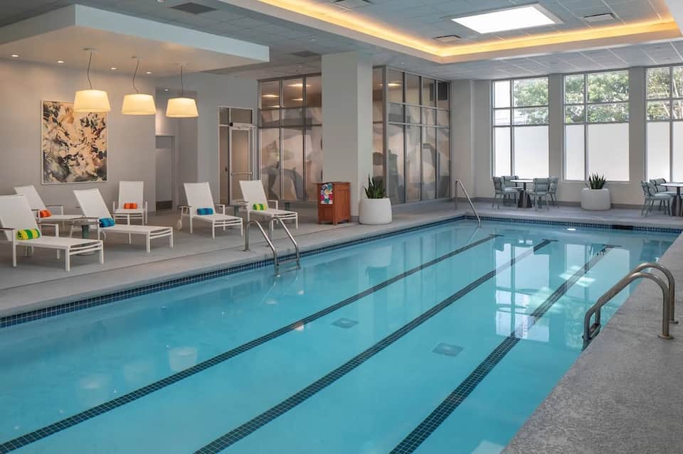 Indoor lap pool with white lounge chairs and modern architectural design