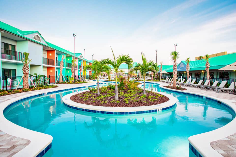 Turquoise resort pool with palm trees and colorful building architecture