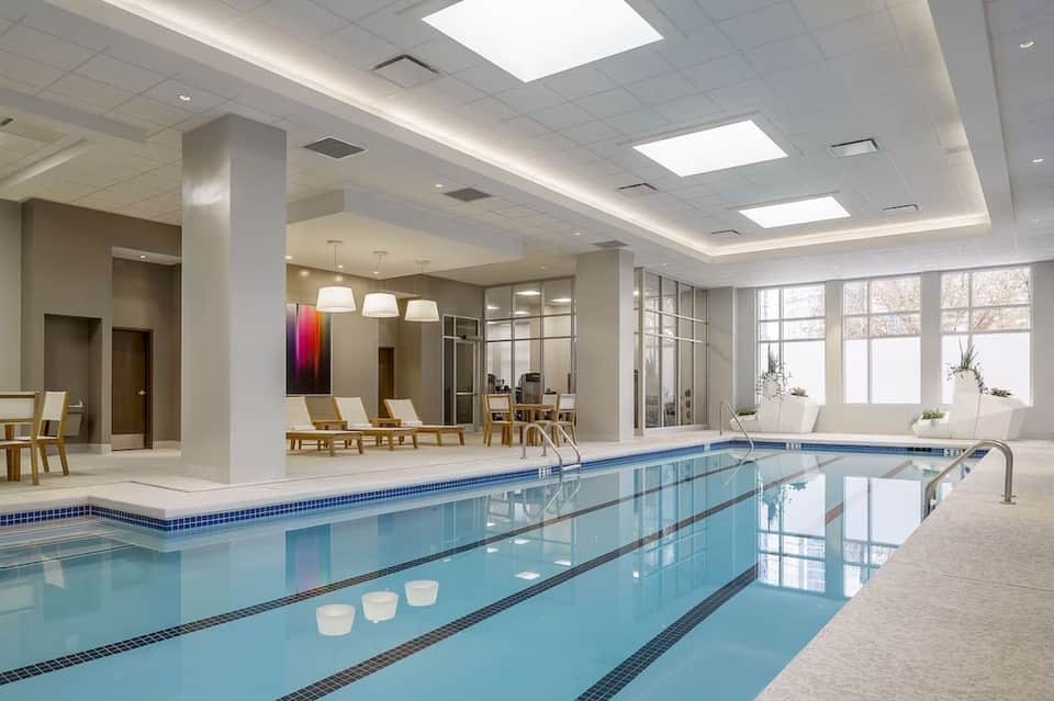 Indoor lap pool with lane dividers, lounge area with natural light from windows and skylights