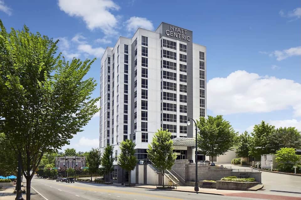 Hyatt Centric hotel high-rise building with white facade, dark windows, and surrounding trees