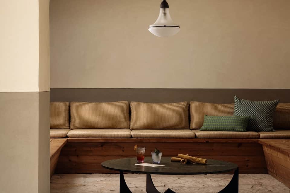 Minimalist lounge area with striped cushioned seating, pendant light, and wooden accents