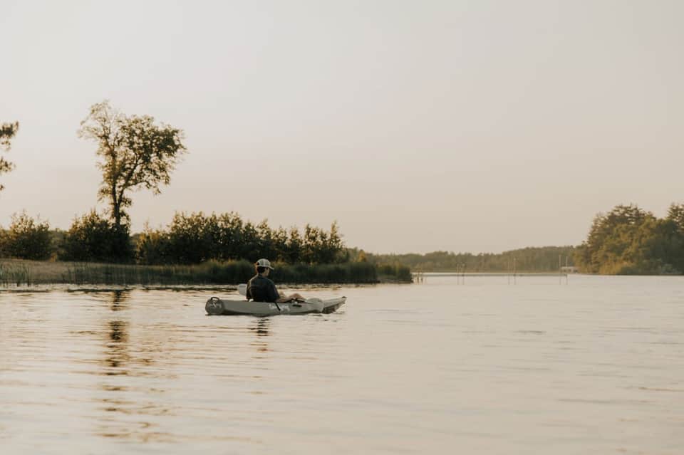 Person in kayak on calm river with forested shoreline in background