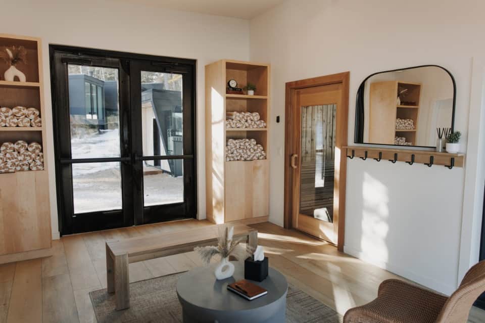 Modern spa lounge with shelving, wooden doors, and black framed mirror