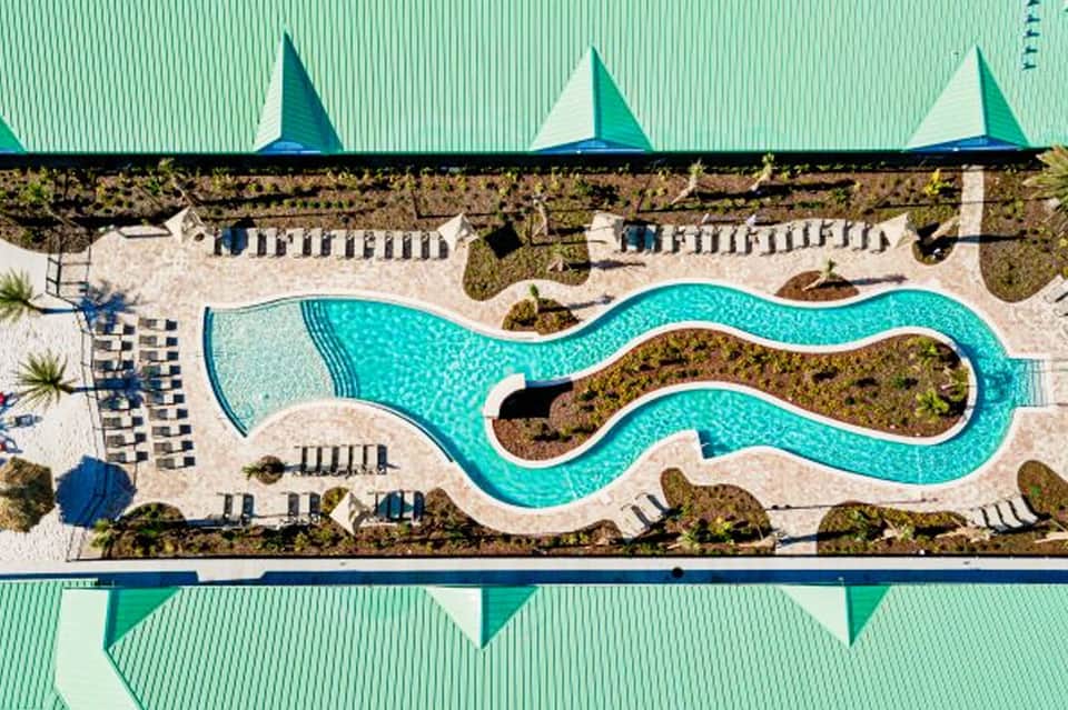 Aerial view of snake-shaped resort pool with turquoise water and beige loungers