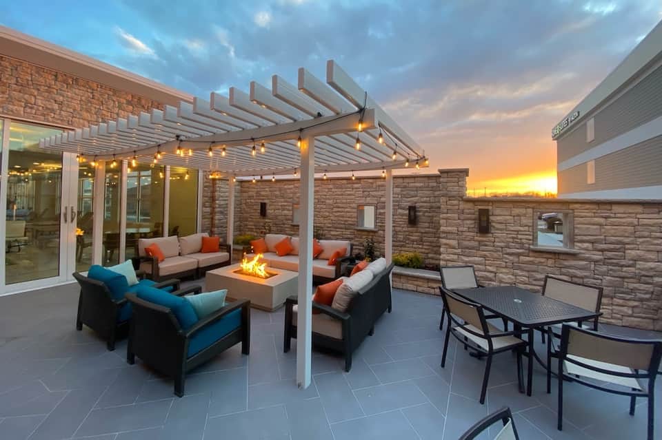 Modern patio with pergola, fire pit, colorful seating, and sunset views at dusk