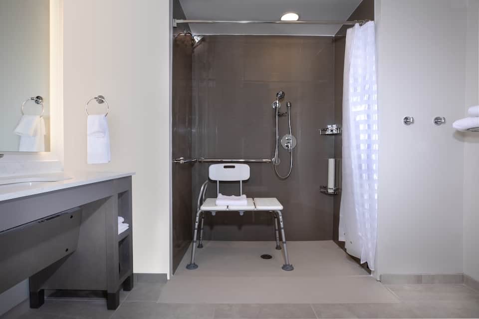 Accessible bathroom with roll-in shower, grab bars, and bench seating for guests with mobility needs.
