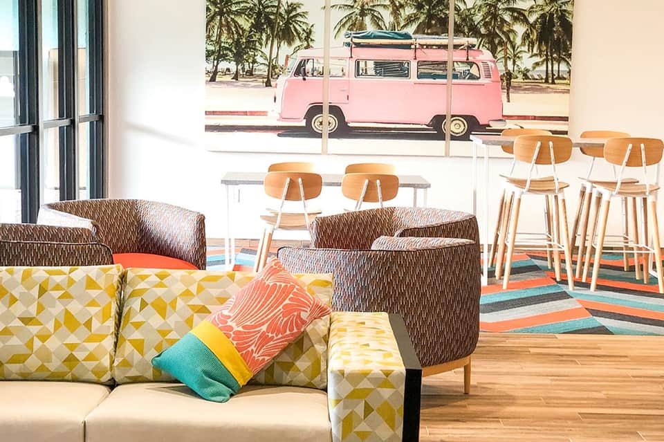 Modern lounge area with colorful patterned furniture and vintage pink bus wall mural