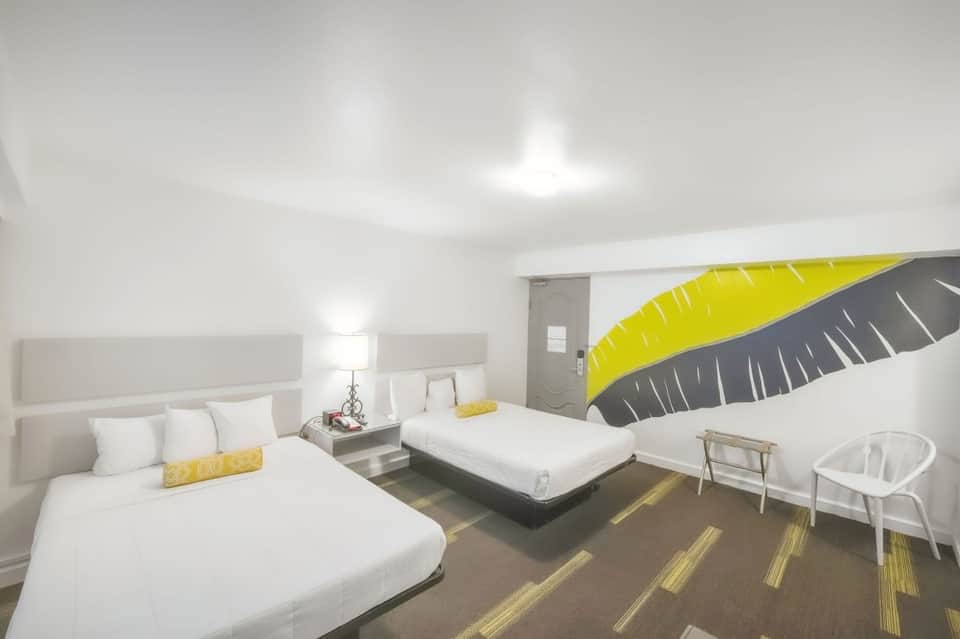 Modern hotel bedroom with two white beds and artistic yellow and gray wing wall mural