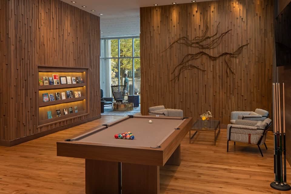 Upscale game room with pool table, wood paneling, built-in shelving, and lounge seating