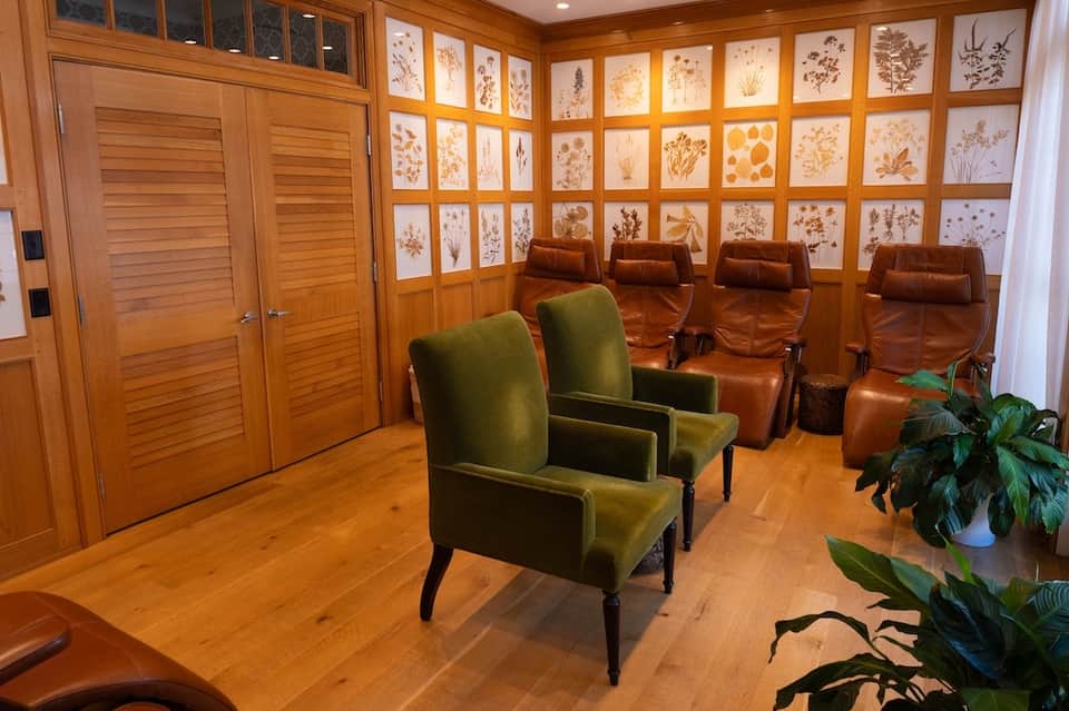 Warm wooden media room with leather seating, wall of framed botanical prints, and modern entertainment setup