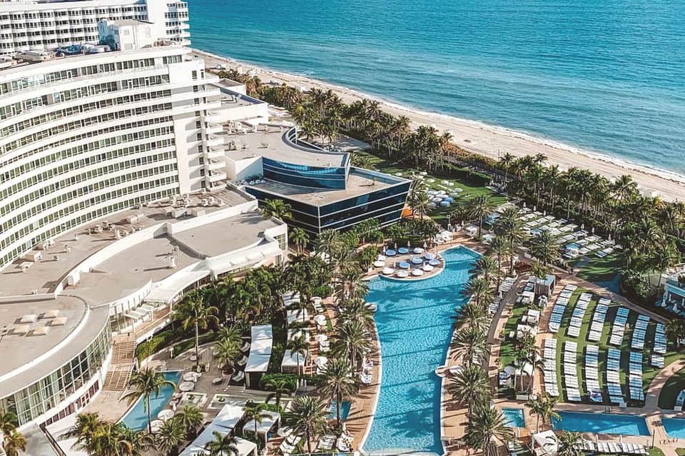 Beachfront resort with curved pool, modern architecture, and high-rise hotel building
