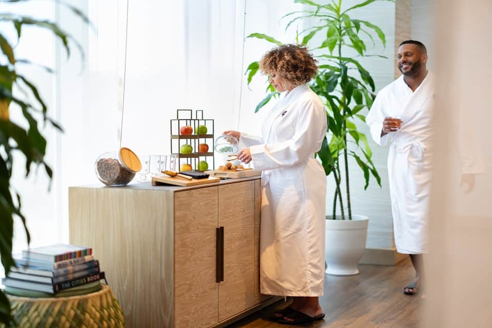 Wellness center with staff in white robes, fruit display, and bright natural lighting