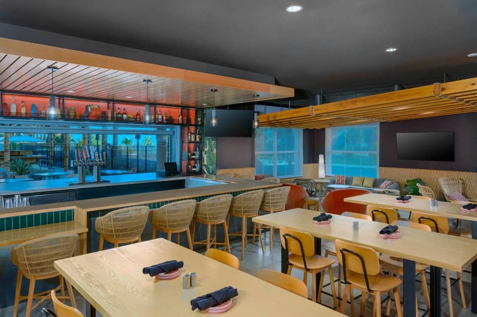 Modern resort dining area with ocean views, wooden seating, bar counter, and colorful panels