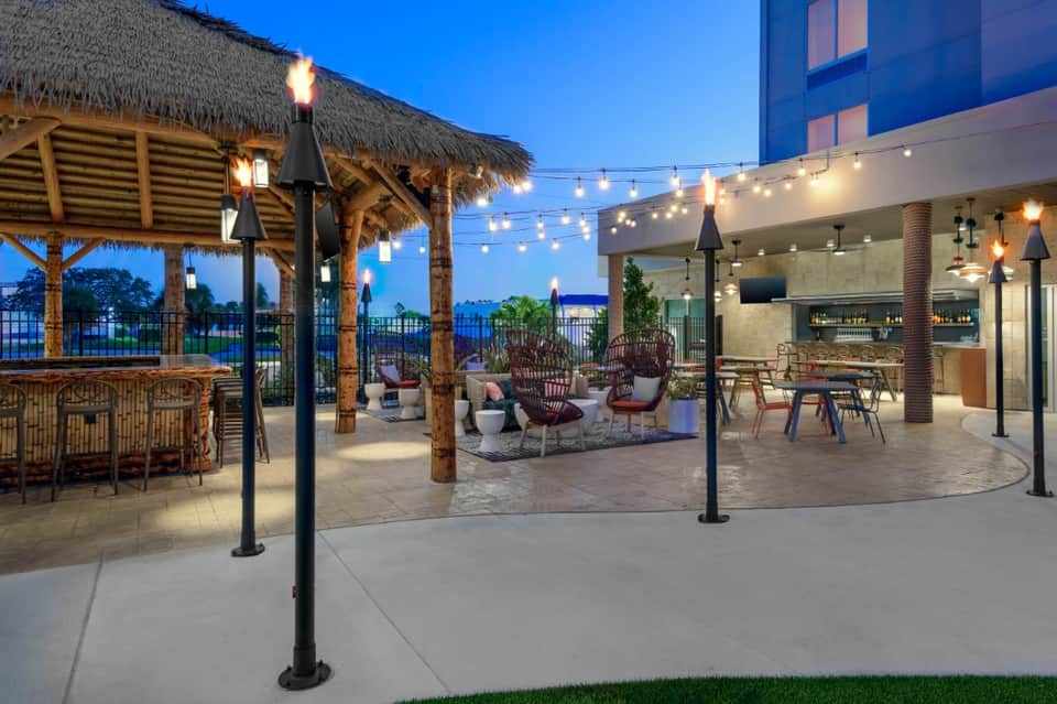 Waterfront rooftop terrace at dusk with lounge seating, pergola, and string lights