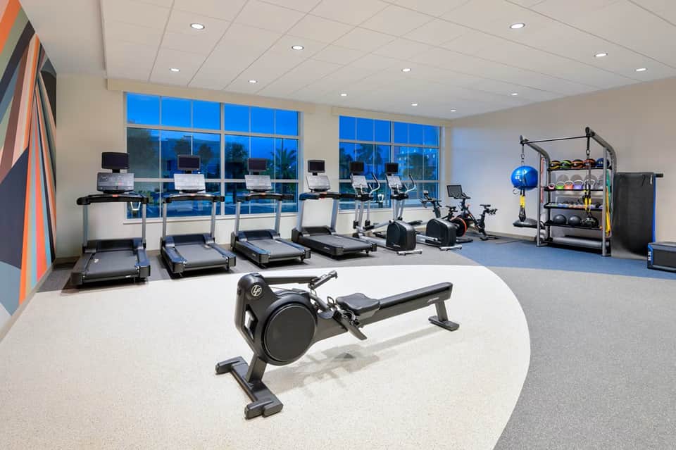 Fitness center with treadmills, exercise bikes, rowing machine, weights, and large windows overlooking grounds