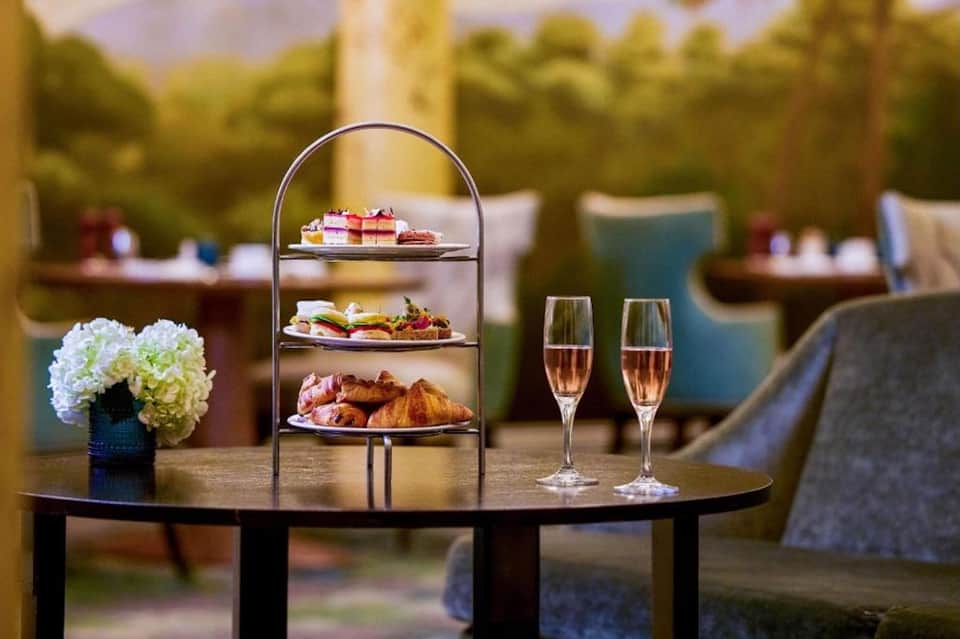 Outdoor afternoon tea service with tiered pastry stand, champagne glasses, and garden seating area