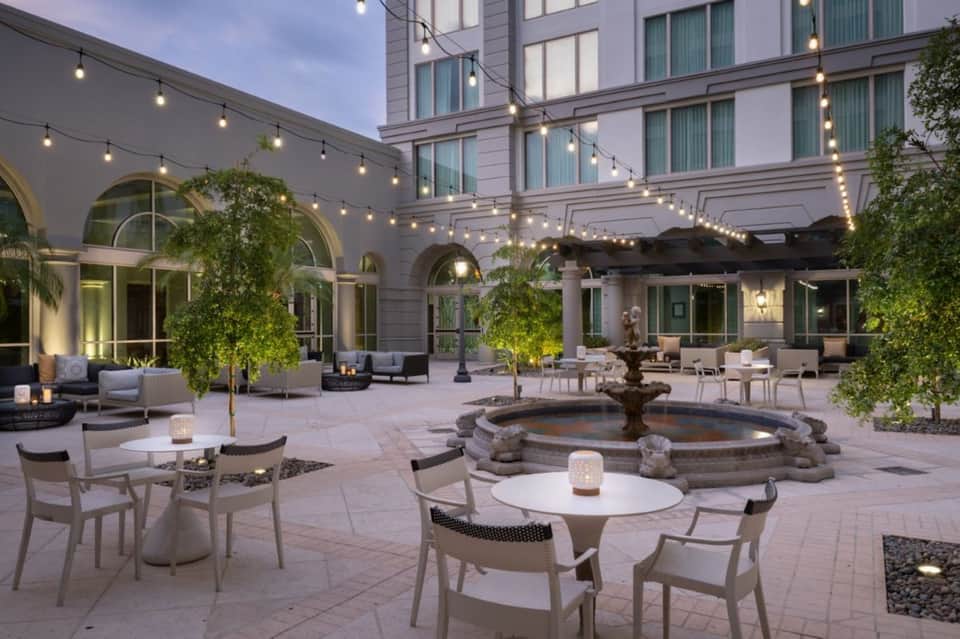 Sophisticated courtyard with fountain, string lights, lounge seating, and building facades