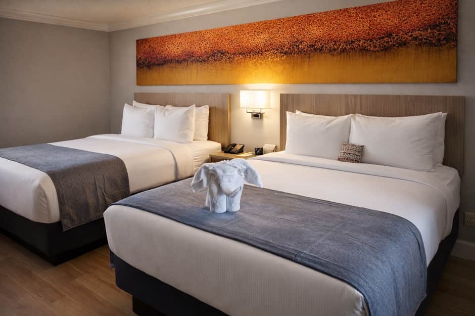 Double occupancy room with two queen beds and sunset landscape wall art