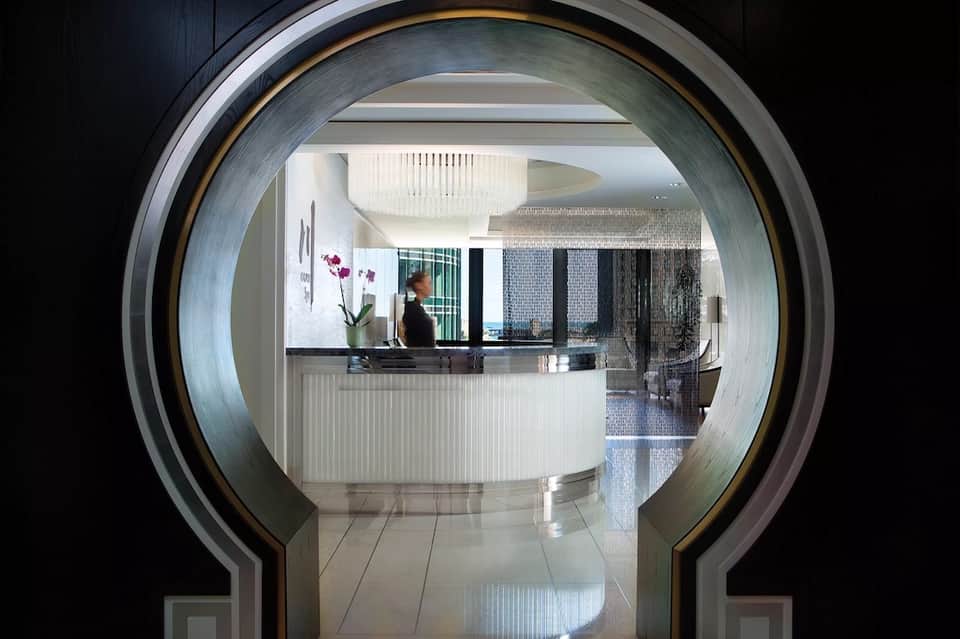Hotel reception desk viewed through modern circular archway with staff member at counter