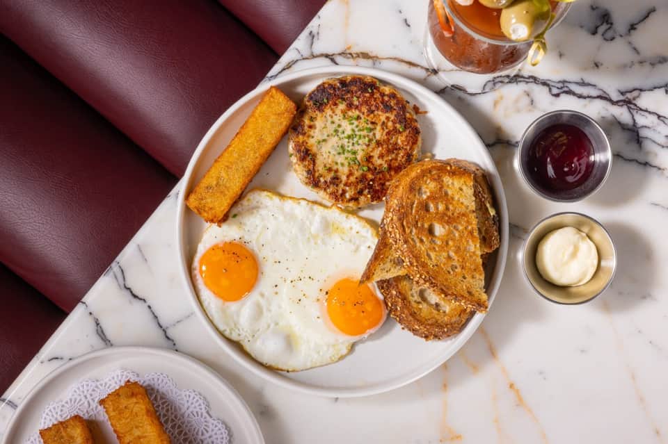 Gourmet breakfast plate with eggs, toast, and pastries on marble table