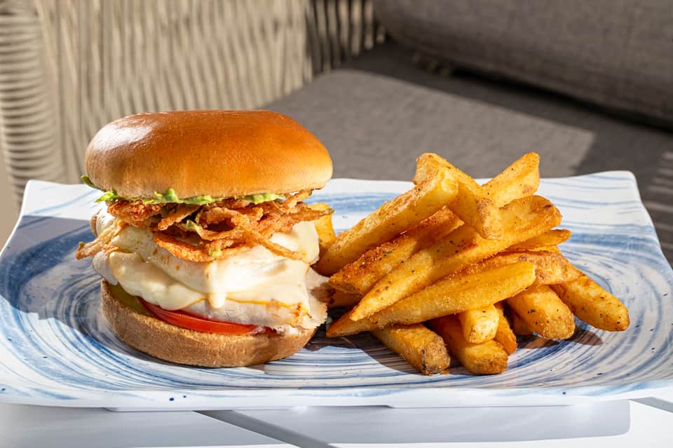 Gourmet burger with crispy onions and fries on blue-patterned plate
