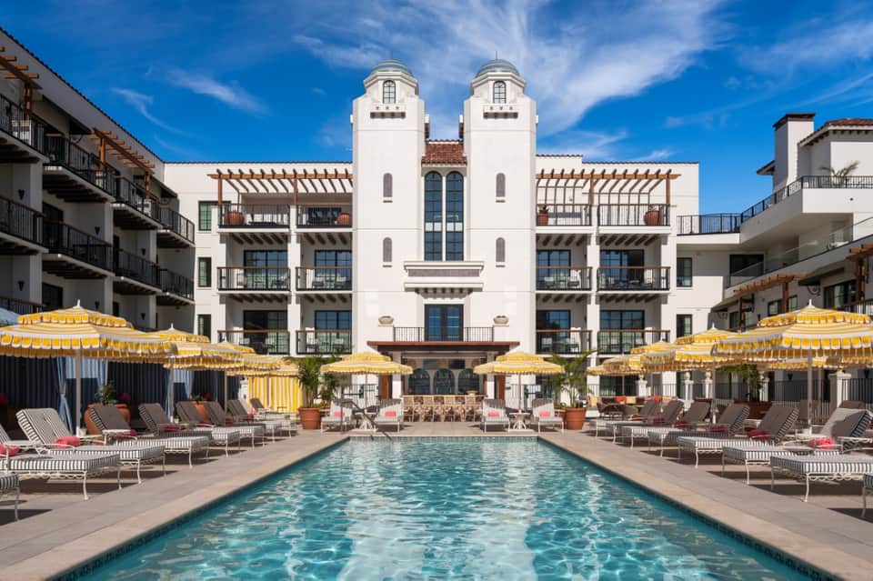 Grand colonial-style resort pool with yellow umbrellas, lounge chairs, and impressive white architecture