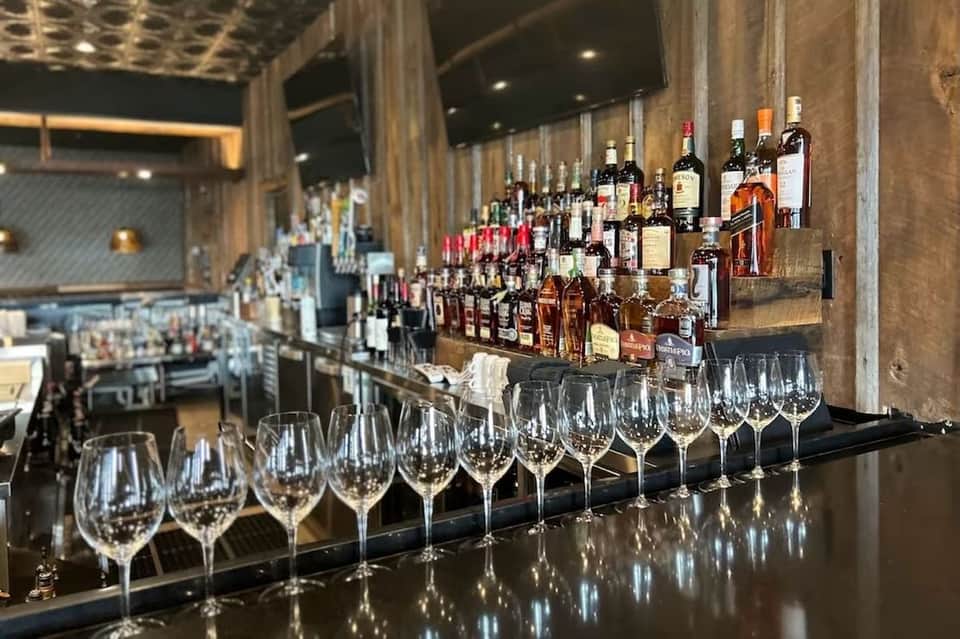 Bar counter with wine glasses and bottles of liquor displayed on shelving